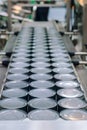 Aluminum cans for food processed in factory line conveyor machine at canned food manufacturing, selective focus