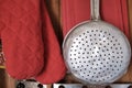 Aluminum colander hangs on the wall of a country house. Kitchen utensils, close-up.