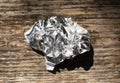 aluminum foil wrap without chocolate candy on a wooden background. Texture of used crumpled aluminium food foil. Royalty Free Stock Photo