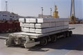 aluminum ingot being transported in wheeled transport container, with view of busy port visible in the background