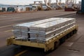 aluminum ingot being transported in wheeled transport container, with view of busy port visible in the background