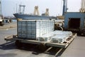 aluminum ingot being transported in wheeled transport container, with view of busy port visible in the background