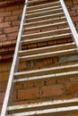 Aluminum ladder at the construction site against the background of a red brick wall. Work at height. Safety engineering Royalty Free Stock Photo