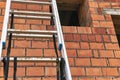 Aluminum ladder at the construction site against the background of a red brick wall. Work at height. Safety engineering Royalty Free Stock Photo