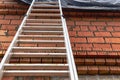 Aluminum ladder at the construction site against the background of a red brick wall. Work at height. Safety engineering Royalty Free Stock Photo