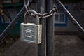 An aluminum padlock hangs on a large iron chain at the gate.