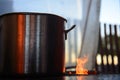 Aluminum pan over wood stove with fire flame beside