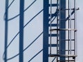 Aluminum roof access ladder detail with safety cage and strong shadow. Royalty Free Stock Photo