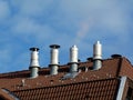 Aluminum stacks on brown clay tile roof under blue sky