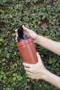 Aluminum thermos mug on hand with green leaves wall