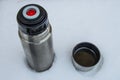 Aluminum thermos for tea or hot drinks, on snowy ground