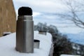 Aluminum thermos for tea or hot drinks, on snowy ground