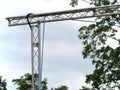 Aluminum truss bridge leading over a footpath with a power cable fixed to it