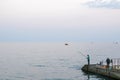 Fishermen at the evening dawn on the sea pier Royalty Free Stock Photo