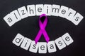 Alzheimers disease text near violet ribbon on black background top view