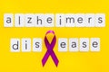 Alzheimers disease text near violet ribbon on yellow background top view