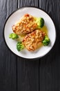 Amandine chicken fillet in almond sauce and broccoli close-up on a plate. Vertical top view