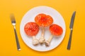 Amanita muscaria fly agaric poisonous mushrooms on plate with fork and knife on yellow background top view.