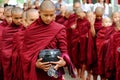 AMARAPURA, MYANMAR - JUNE 28, 2015: Buddhist monks queue for lun