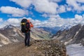 An amateur mountaineer photographer with a large backpack on his shoulders captures the view of