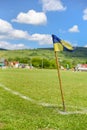 Amateur soccer field, retro corner flag on the foreground, football players are fighting for the ball on the background Royalty Free Stock Photo