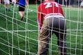 Amateur senior goalkeeper in red uniform under number 21 playing soccer with friends at playground in public
