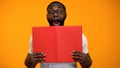 Amazed African-American man looking out book, interesting information, studying