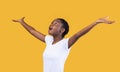 Amazed African Lady Spreading Raised Hands Looking Up, Yellow Background