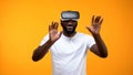 Amazed Afro-American man in VR headset exploring modern technologies, future