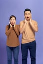 Amazed asian couple expressing shock, purple studio background