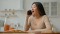 Amazed Asian japanese woman in domestic kitchen talking mobile phone with friend listen good news gossip multiethnic Royalty Free Stock Photo
