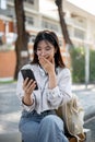 An amazed Asian woman is looking at her phone screen, surprised with an unexpected news Royalty Free Stock Photo