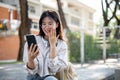 An amazed Asian woman is looking at her phone screen, surprised with an unexpected news Royalty Free Stock Photo