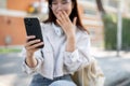 An amazed Asian woman is looking at her phone screen, surprised with an unexpected news Royalty Free Stock Photo