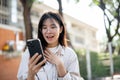 An amazed Asian woman is looking at her phone screen, surprised with an unexpected news Royalty Free Stock Photo