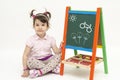 Amazed baby girl draw flowers and bike on black board with chalk Royalty Free Stock Photo