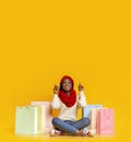 Amazed black girl with purchases pointing up at empty space Royalty Free Stock Photo