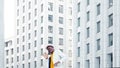 Amazed black guy in yellow t shirt and white suit dances contemporary dance against megalopolis office buildings