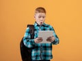Amazed boy schooler with backpack using digital tablet Royalty Free Stock Photo