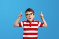 Amazed boy wearing striped red shirt and eyeglasses, pointing up with opened mouth while having idea Royalty Free Stock Photo