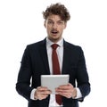 Amazed businessman holding tablet and gasping