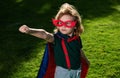 Amazed child superhero hero in red cloak in nature.