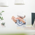 Amazed child using virtual reality headsets trying to grab unexisting virtual objects while sitting at the dinner table. Royalty Free Stock Photo