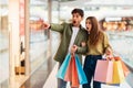 Amazed Couple Doing Shopping Pointing Finger Aside In Mall Royalty Free Stock Photo