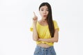 Amazed and excited attractive young slim female model in cropped yellow t-shirt with long dark hair folding lips raising