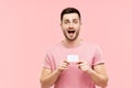 Amazed excited man with open mouth holding credit card over pink background