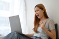 Amazed and excited young Asian woman receiving unexpected news through her laptop computer Royalty Free Stock Photo