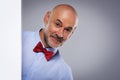 Amazed face man wearing bow tie and looking out of white board while standing at isolated background Royalty Free Stock Photo