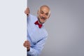 Amazed face man wearing bow tie and looking out of white board while standing at isolated background Royalty Free Stock Photo