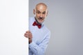 Amazed face man wearing bow tie while looking out of white board while standing at isolated background Royalty Free Stock Photo